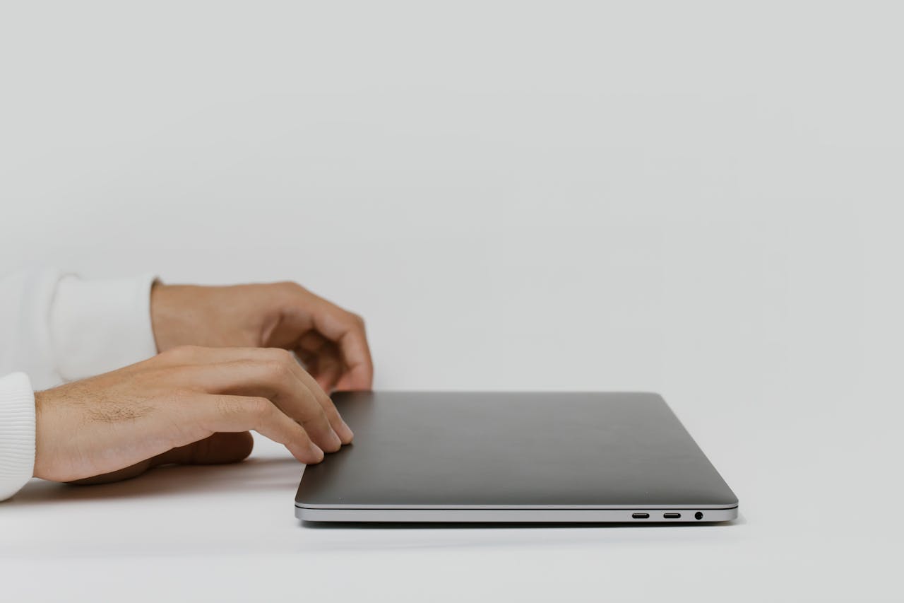 Services Hands preparing to open a closed laptop on a minimalist desk, ready for work.