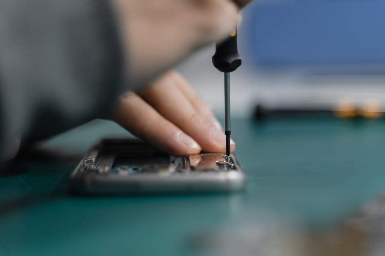 Expertos en celulares Detailed shot of smartphone repair with a screwdriver and hand close-up.