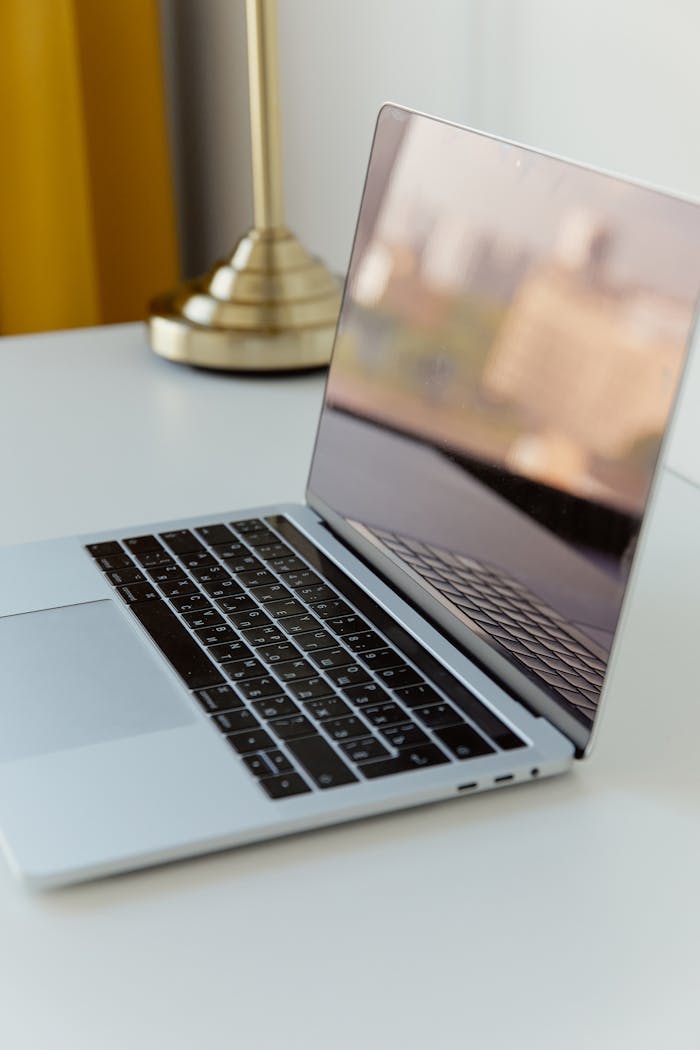 Services A modern laptop on a white desk with a brass lamp, minimalistic and sophisticated.